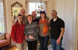 3 men and their female partners standing in front of a Christmas tree