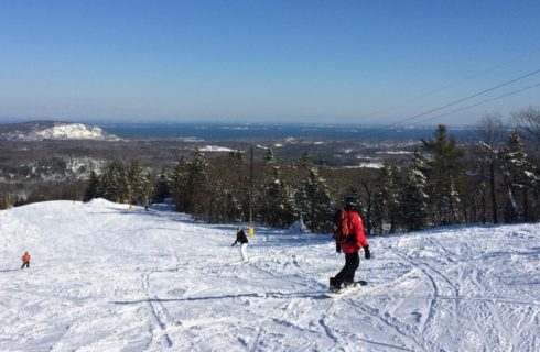 A skier and snowboarder going down a ski slope with a lot of white powder